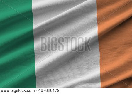 Ireland Flag With Big Folds Waving Close Up Under The Studio Light Indoors. The Official Symbols And