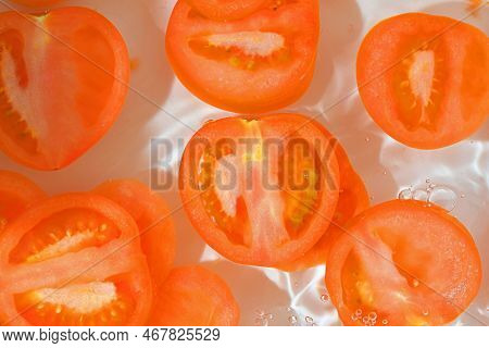 Close-up View Of The Red Tomato Slices In Water Background. Texture Of Cooling Vegeteble Drink With 