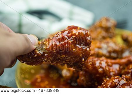 Hand Holding Korean Spicy Deep-fried Chicken Topped White Sesame. Korean Food Style.