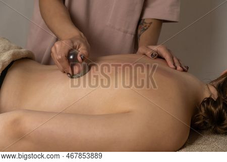 Massage Therapist In A Spa Salon Does A Massage With A Vacuum Jar On His Client's Back For A Healing