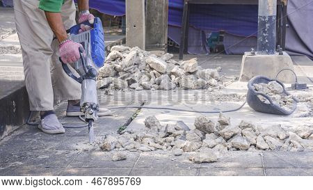 Cropped Image Of Road Worker Using Jackhammer Drilling Footpath On Roadside Area For Install Undergr