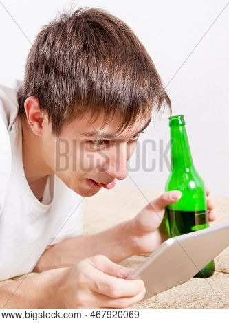 Young Man With A Beer And Tablet Computer Shows The Tongue To The Screen