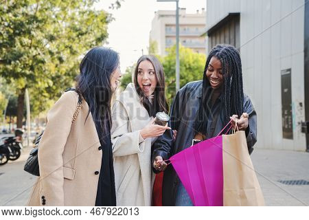 Group Of Mutiethnic Happy Young Women Suprised Looking Inside Of A Shopping Bag Outdoors. Three Shop