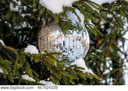 Christmas Disco Ball Decoration On A Snowy Fir Tree Branch. Selective Focus, Shallow Depth Of Field