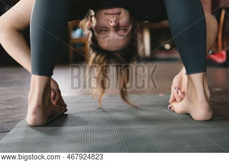 Close-up Photo Of A Female New Yoga Teacher Doing A Standing Forward Fold Pose Variation Hooking Big