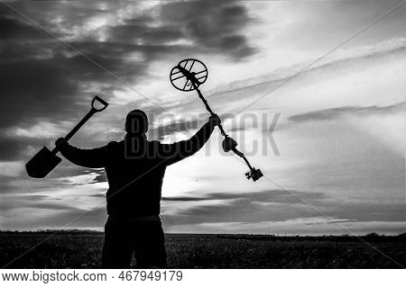 A Happy Treasure Hunter With A Metal Detector On The Background Of A Beautiful Sunset