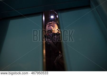 Man Repairing An Elevator At Night Inside A Shaft Of A High-rise Building, Front And Background Blur