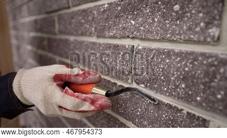 The Master Tiled The Facade Of The House. The Builder Closes The Seams In The Brickwork. Finishing T