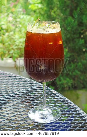 Closeup Of A Glass Of Iced Coffee With Blurry Green Foliage In The Backdrop