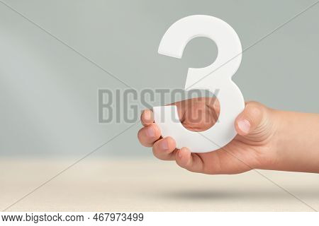 Number Three In Hand. Hand Holding White Number 3 On Blurred Background With Copy Space. Concept Wit