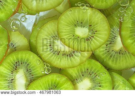 Slices Of Kiwi Fruit In Water On White Background. Kiwi Fruit Close-up In Liquid With Bubbles. Slice