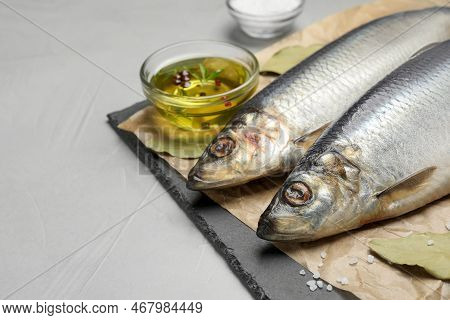 Slate Plate With Salted Herrings, Oil And Spices On Grey Table, Closeup. Space For Text