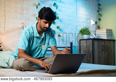 Young Man Busy Woking On Laptop Uring Night On Bed - Concept Of Over Working, Work From Home And Pro