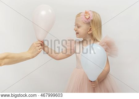 Little Girl In Pink Dress Smiling Takes Balloon From Female Hand. Little Blonde Princess On White Ba