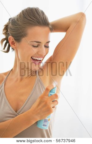 Happy Young Woman Applying Deodorant On Underarm