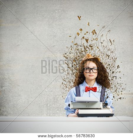 Young funny woman in glasses using typewriter