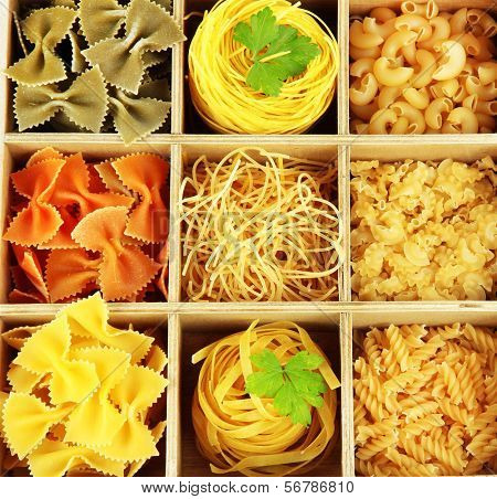 Nine types of pasta in wooden box sections close-up isolated on white
