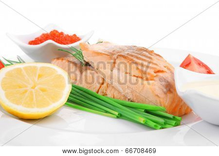 healthy fish cuisine : grilled pink salmon steaks with red caviar lime and sauces on white dish isolated over white background