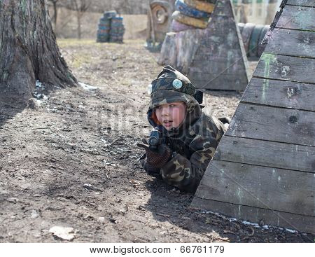 Little boy player with gun during laser tag game.