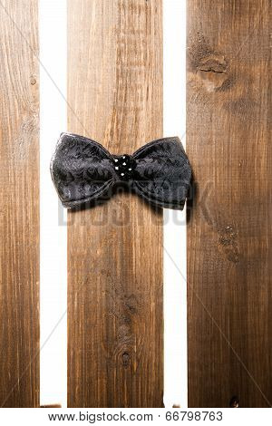 Black handmade bow tie over wooden background