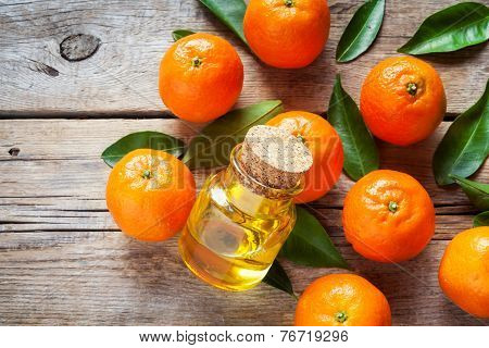 Tangerines With Leaves And Bottle Of Essential Citrus Oil On A Wooden Table.