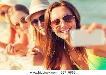 summer vacation, travel, technology and people concept - close up of smiling women in sunglasses and hats making selfie with smartphone on beach