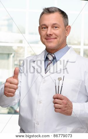 Dentist with tools showing thumb up