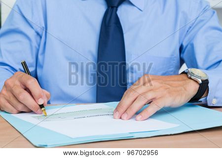 Businessman writing a contrat before signing it in the office