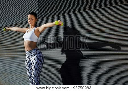 Athletic female with perfect figure getting her arms in great shape while lifting weights
