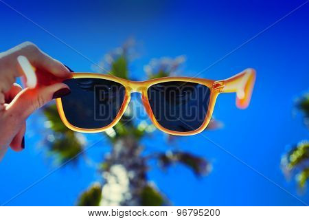 First person shot looking through glasses on palm tree and blue sunny sky