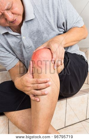 Matured man suffering from painful knee joint seated on steps