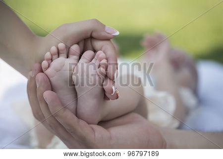 Happy family of mother and father touching bare feet with small toys