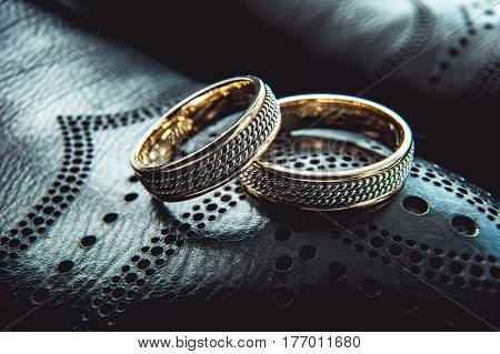 unusual luxery wedding rings on the dark perforated leather of a shue