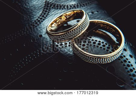 unusual luxery wedding rings on the dark perforated leather of a shue