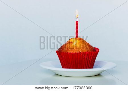 Isolated muffin with a red candle on white background