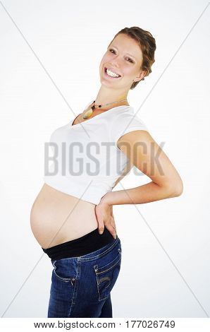 Happy smiling heavily pregnant young woman showing her growing baby bump in profile on white background.