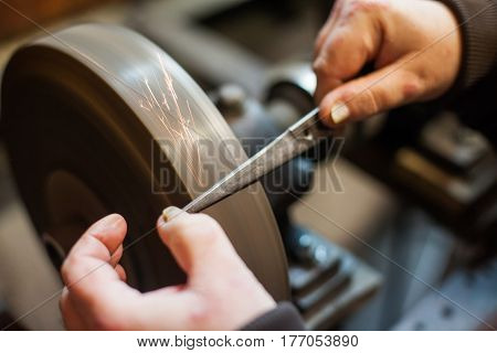 Close up shot of a man's hands sharpening a scissors.