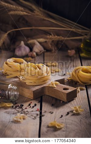 Raw homemade pasta with flour and spices on the rustic background. Uncooked noodles.