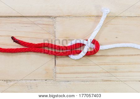 sheet bend knot made with red rope on wooden background