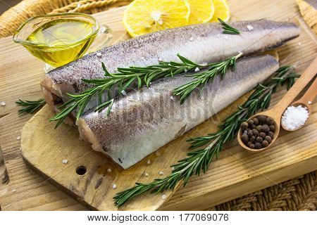 Raw fish hake with spices and sea salt oil on the board