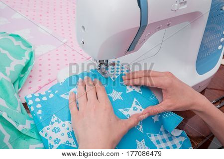 Woman's hands with dress at sewing machine close up