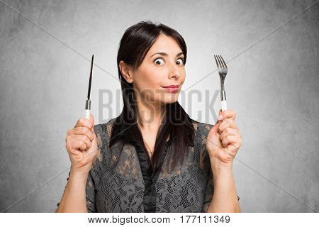 Hungry woman holding fork and knife