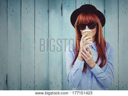 Digital composite of Woman with coffee and hat against blue wood panel