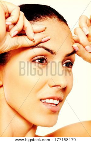 Worried young woman checking wrinkles on forehead