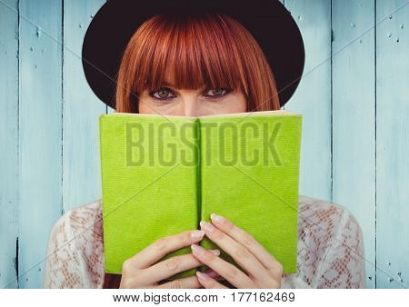 Digital composite of Woman with green book against blue wood panel