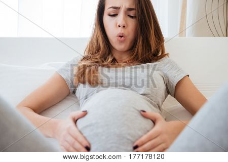 Cropped image of Pregnant woman with tummy-ache which lying on bed in home