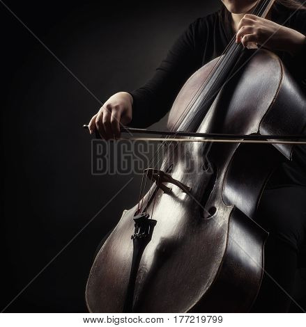 Close-up of cellist playing classical music on cello on black background