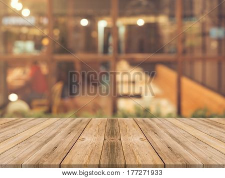 Wooden board empty table top on of blurred background. Perspective brown wood table over blur in coffee shop background - can be used mock up for montage products display or design key visual layout.