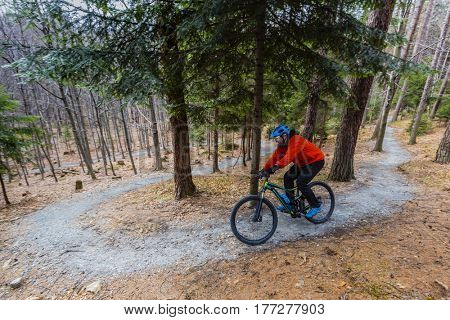 Mountain biker riding on bike in early spring mountains forest landscape. Man cycling MTB enduro flow trail track. Outdoor sport activity.