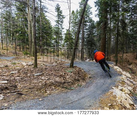 Mountain biker riding on bike in early spring mountains forest landscape. Man cycling MTB enduro flow trail track. Outdoor sport activity.